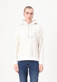 Hooded sweatshirt in cream with a geometric pattern, featuring a front kangaroo pocket, white ribbed cuffs, and a small logo detail.