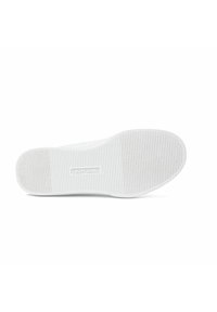 Suola di sneaker bianca in gomma testurizzata. Presenta scanalature per la presa e un logo in rilievo al centro. Finitura liscia complessiva.