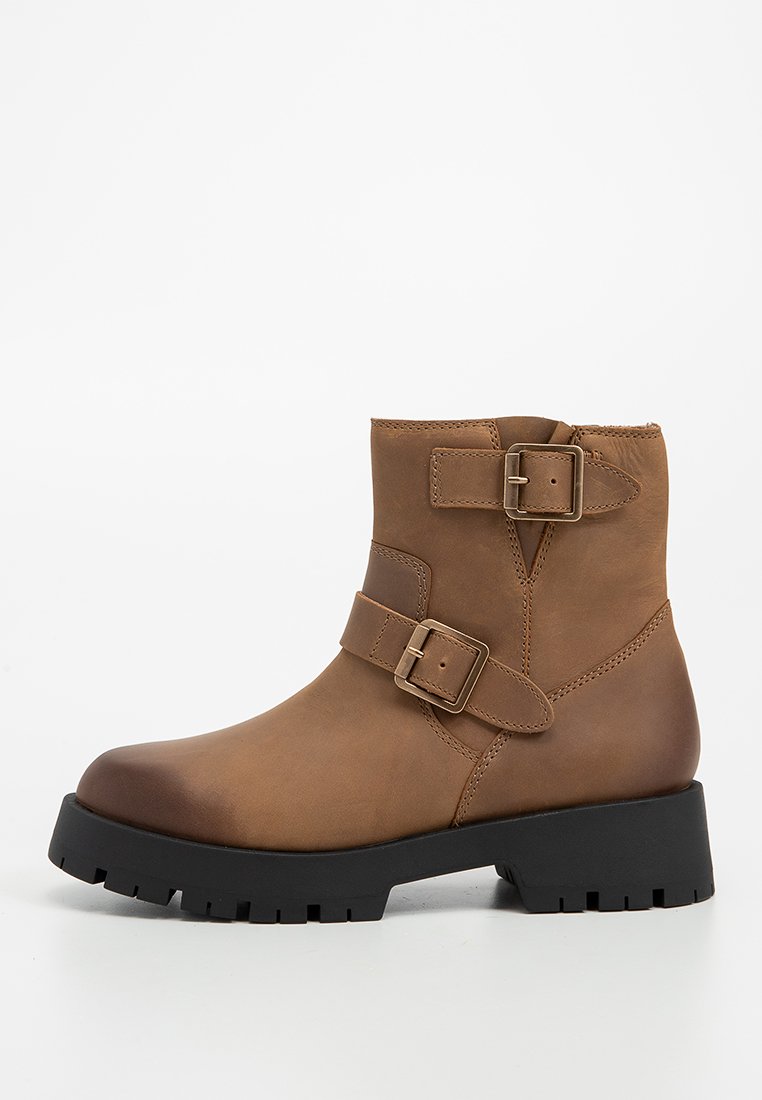 Bota de cuero marrón hasta el tobillo con dos hebillas decorativas, punta redondeada, tacón resistente y suela texturizada negra.