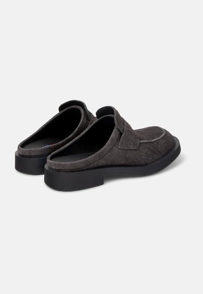 Grå slip-on sko med en blød, struktureret overdel og en holdbar sort sål. Rund form med lav hæl og ingen synlige snørebånd eller hardware-detaljer.