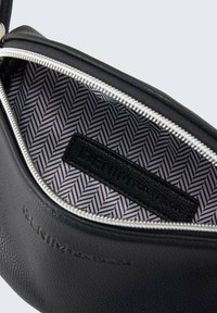 Borsa in pelle nera con zip argentata, con una fodera in tessuto a spina di pesce e un'etichetta nera impressa con "DENIM TOM TAILOR."