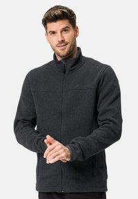 Veste en polaire gris foncé avec un col haut, une fermeture éclair à l'avant et une surface texturée. Comprend des poches latérales et des poignets ajustés.