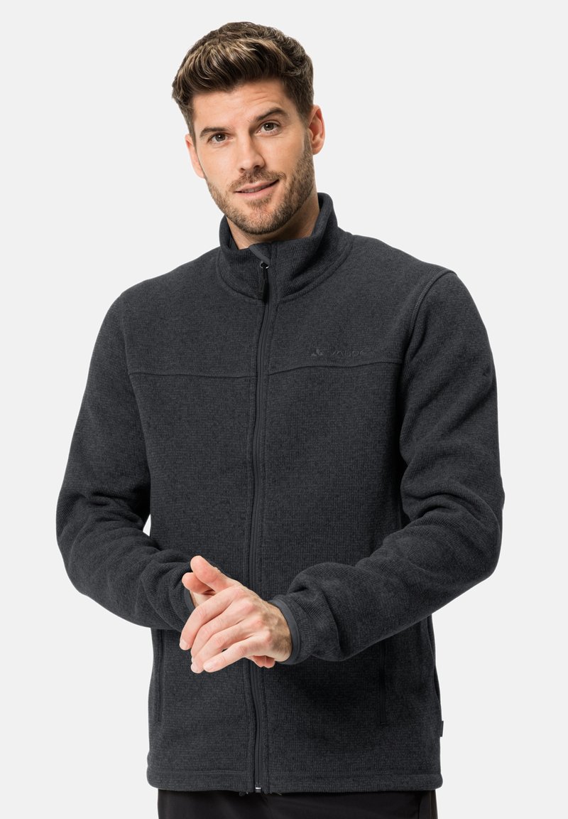 Veste en polaire gris foncé avec un col haut, une fermeture éclair à l'avant et une surface texturée. Comprend des poches latérales et des poignets ajustés.