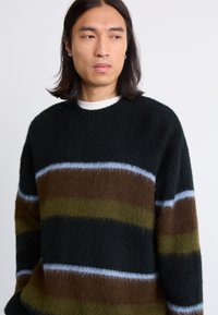 Overdimensioneret sweater i sort med vandrette striber i brun, grøn og lyseblå. Strikket tekstur, rund hals, blødt materiale.