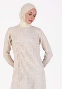 Beiges langärmliges Kleid mit strukturiertem vertikalem Strickmuster in der Mitte. Weicher Stoff und runder Ausschnitt, ergänzt durch ein passendes Kopftuch.