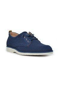 Zapatos de malla azul marino con un acabado texturizado, suela de goma blanca y acentos de cordones marrones en contraste, presentando un diseño aerodinámico.