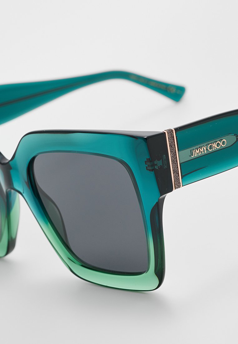 Lunettes de soleil carrées avec dégradé vert, verres sombres et logo doré "Jimmy Choo" sur la branche.