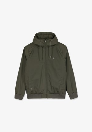 Veste à capuche vert olive avec une fermeture éclair sur le devant, des poignets côtelés et deux poches latérales. Présente un petit logo sur la poitrine. Tissu lisse.