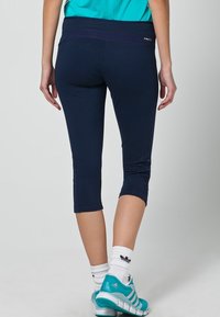Navy capri leggings med bred midjeband, som har lila sömnadsdetaljer, slät textur och en åtsittande design.