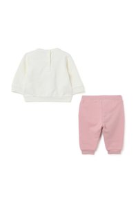 Witte lange mouwen top met knoopdetail en roze joggingsbroek met elastische tailleband, beide gemaakt van zachte, comfortabele stof.