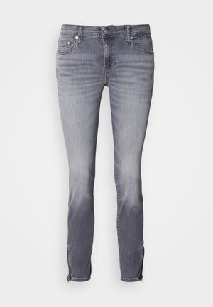Jeans de mezclilla gris con un corte ajustado, que presentan una textura desgastada y dobladillos con cremallera. La cinturilla incluye un botón y trabillas para el cinturón.
