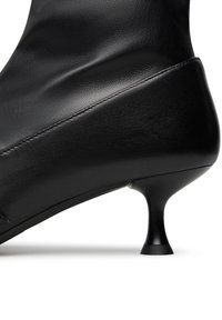 Stivale ankle in pelle nera con una texture liscia, punta affusolata e tacco sottile. Presenta un dettaglio delle cuciture lungo il lato per un tocco di design in più.