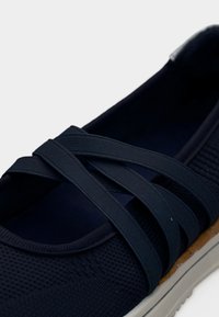 Ναυτικό μπλε παπούτσι τύπου slip-on με διασταυρούμενους ελαστικούς ιμάντες, υφασμάτινο επάνω μέρος με υφή και λευκή μαλακή σόλα με λεπτομέρεια φελλού.