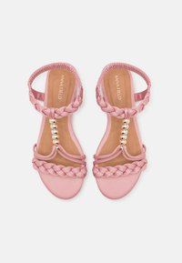 Pink sandals with braided straps, a smooth textile upper, and a gold bead accent. Flat soles with a cushioned footbed for comfort.