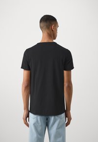 Black cotton t-shirt with a round neck and short sleeves, featuring a plain design and a slightly curved hem at the back.