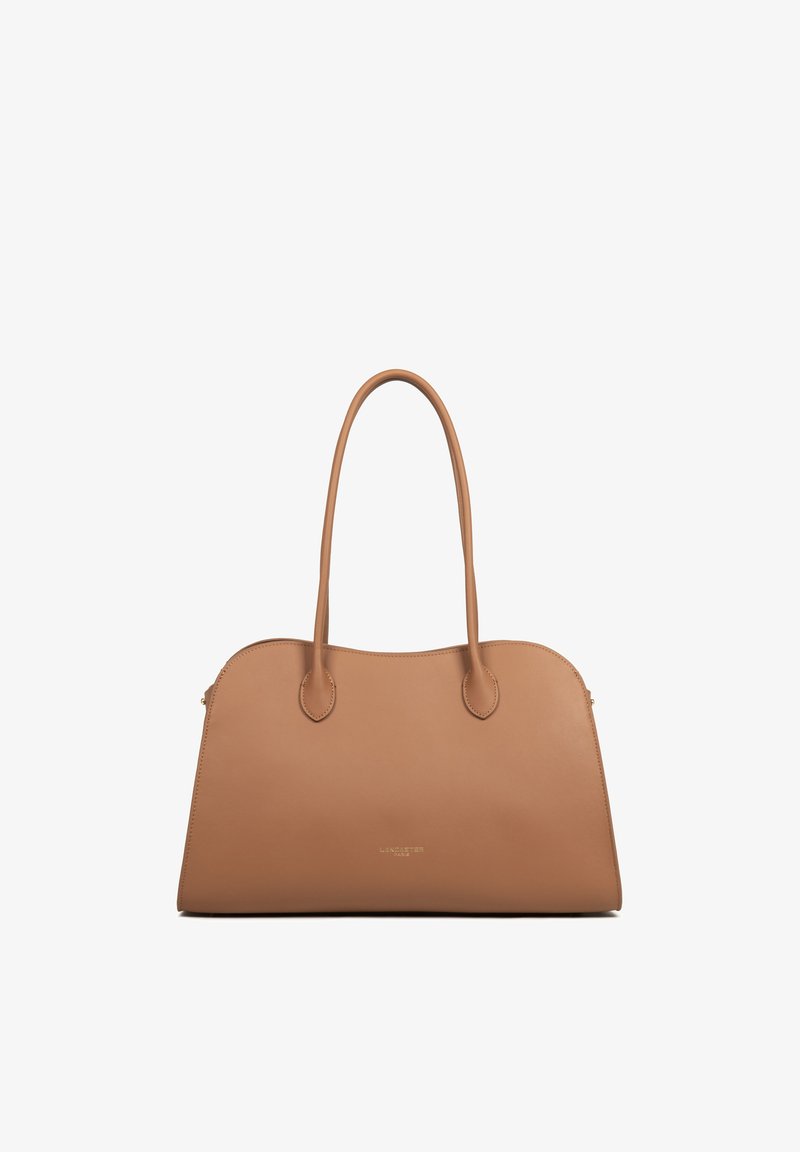 Sac à main en cuir couleur cognac avec double poignées longues et logo de la marque subtil centré près du bas, posé debout sur un fond blanc.