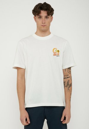 Ung mand med kort krøllet hår iført en hvid T-shirt med teksten "Go for it!" og et smilende ansigt, som viser tatoveringer på højre underarm.