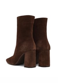 Botas de tobillo de ante marrón con punta redondeada, tacón alto en bloque y textura suave. Diseño minimalista, sin marcas ni acentos visibles.