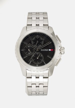 Montre en acier inoxydable argenté avec un cadran noir, affichage de la date et trois sous-cadrans. Elle dispose d'un bracelet à maillons et d'index horaires bien visibles.