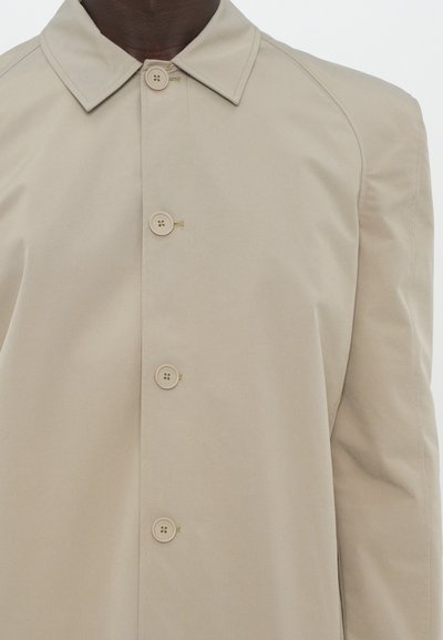 Beige trench coat with a smooth texture, featuring a pointed collar and six rounded buttons down the front, cut in a relaxed fit.