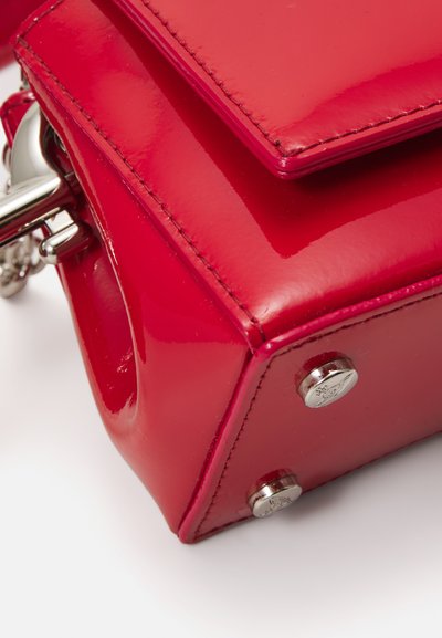 Red patent leather handbag featuring a structured design, smooth texture, top flap, and silver hardware accents.