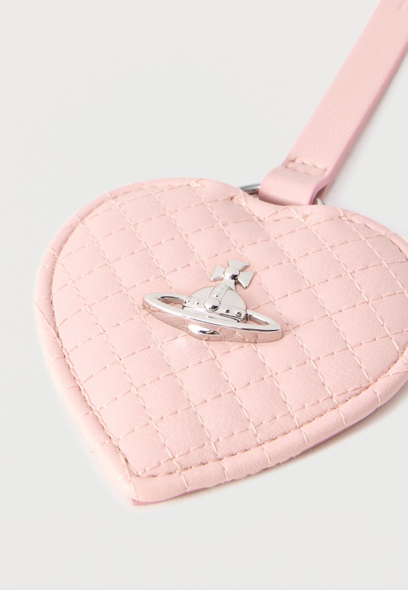 Accessorio rosa trapuntato a forma di cuore con un emblema a forma di globo e croce argentati, attaccato a una cinghia abbinata.