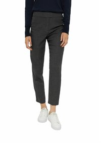 Pantalones a cuadros en blanco y negro con corte slim, cintura a media altura y largo hasta los tobillos, combinados con zapatillas blancas. Textura de tela suave.