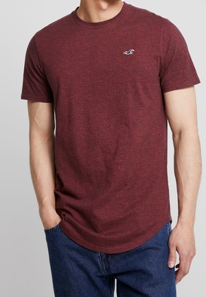 Bordeauxfarbenes Kurzarm-T-Shirt aus einem weichen, gemischten Stoff mit einem Rundhalsausschnitt und abgerundetem Saum, das ein kleines weißes Logo auf der Brust trägt.