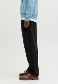 Lysblå sweatshirt, hvid T-shirt, sorte joggers og brune sko. Har en afslappet pasform og blødt materiale, med synlige syninger.