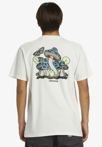 White cotton t-shirt featuring a colorful graphic of mushrooms, a butterfly, and a frog on the back, with a screen-printed logo.