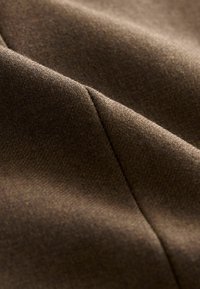 Material textil maro cu o textură fină, având un luciu subtil, cu linii diagonale discrete și o suprafață netedă. Materialul pare țesut și durabil.