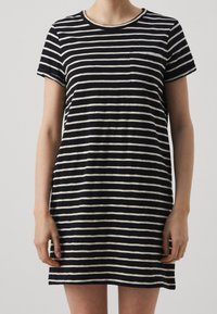 Robe t-shirt rayée noire et crème avec manches courtes, encolure ronde et une poche avant. Tissu en coton doux et décontracté.