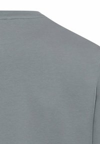 Szara koszulka, bawełniany materiał, okrągły dekolt, krótkie rękawy, gładka struktura, minimalistyczny design, brak widocznych wzorów czy grafik.