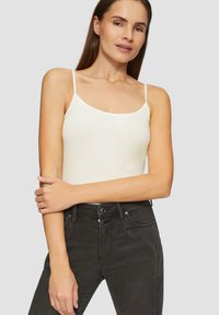 Witte mouwloze tanktop met dunne banden, gemaakt van een gladde katoenkwaliteit, gecombineerd met hoge zwarte jeans met zichtbare stiksels.
