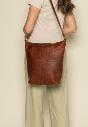 Hnědá kožená kabelka přes rameno s texturovaným krokodýlím vzorem, se zlatými kovovými detaily a popruhem přes tělo.