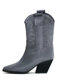 Botină cowboy gri din suede sintetic, cu vârf ascuțit, decupaje decorative și toc stratificat. Dispune de un mânere pentru a fi ușor de încălțat.