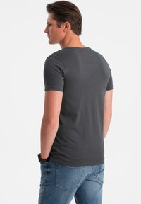 Šedé tričko s krátkým rukávem, klasickým kulatým výstřihem, vyrobené z měkké bavlny. Tkanina je hladká a má uvolněný střih.