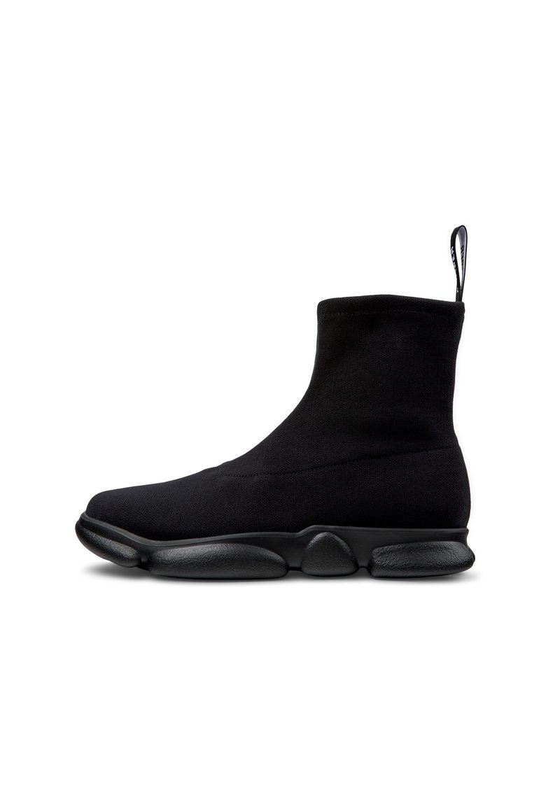 Botas de tobillo de punto negras con una suela de goma cilíndrica, que presentan una textura suave y una pestaña en la parte posterior para facilitar su colocación.