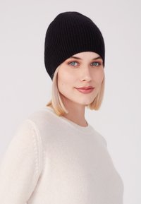 Czarna, prążkowana czapka beanie o dopasowanym kroju. Materiał wydaje się być miękki, o gładkiej fakturze i delikatnym rozciągnięciu.