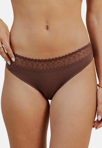 Sous-vêtements marron avec des dentelles, fabriqués dans un tissu doux, de coupe basse, et présentant une texture côtelée subtile sur les côtés.