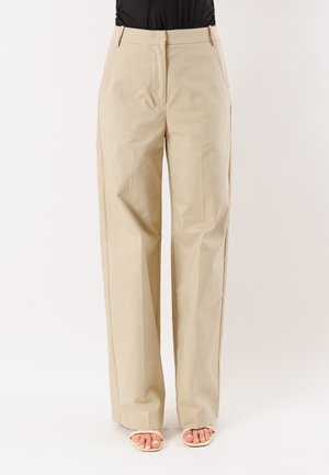 Pantaloni beige a vita alta e gamba larga indossati con sandali aperti beige e top nero infilato, vista frontale.