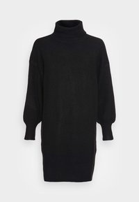 Svart polotröja, mjukt stickat tyg, oversized passform, sänkt axel, långa puffärmar, sidoflikar i fållen för ökad rörlighet.