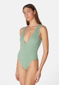 Grön strukturerad enstyckad baddräkt med djup V-halsringning, breda axelremmar och högt skurna ben, designad för en tajt passform och stiligt utseende.