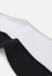 Calcetines de rayas blancas y negras, con una textura acanalada y un acabado suave, colocados diagonalmente en la imagen.