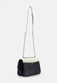 Axelväska med en marinblå läderbotten, krämfärgad vadderad topp och silverkedjesnodd. Har en logotyp framtill.