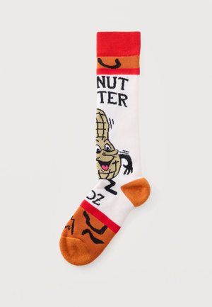 Chaussette avec un personnage d'arachide animé souriant, pointe et talon orange, bord-côte rouge, et texte partiel affichant "NUTTER."