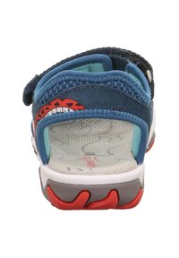 Sandale bleue avec une semelle intérieure texturée, une sangle réglable et un design vibrant rouge et noir sur le talon. Semelle en caoutchouc avec des couleurs d'accent.