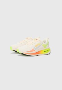 Lightweight running shoes featuring a mesh upper in pale peach, with neon green and orange accents. ZoomX cushioning and rubber outsole.