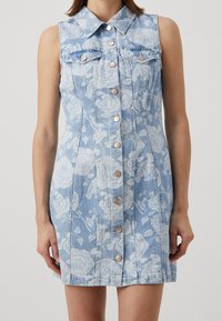 Light blue denim dress featuring a floral pattern, sleeveless design, pointed collar, front buttons, and chest pockets. Soft texture.