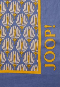 Zijden sjaal met een blauwe achtergrond, witte bloempatronen en gele accenten. De merknaam "JOOP!" is in het geel gedrukt.